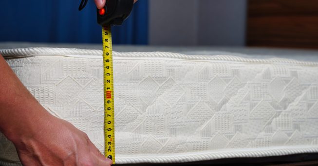 Measuring the height of the mattress with a measuring tape. Comfortable sleep orthopedic bed. High quality photo