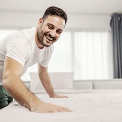 A tidy morning man making his bed in the morning at his cozy home.