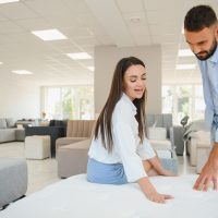 A young couple is choosing bedding at a bed, mattress and pillow store. Everything for a comfortable sleep.