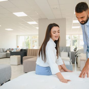 A young couple is choosing bedding at a bed, mattress and pillow store. Everything for a comfortable sleep.