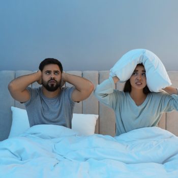 Young couple suffering from noisy neighbours in bed at home