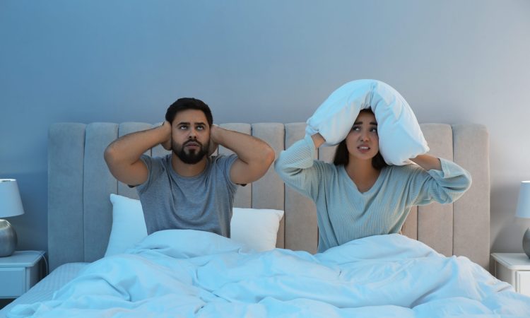 Young couple suffering from noisy neighbours in bed at home